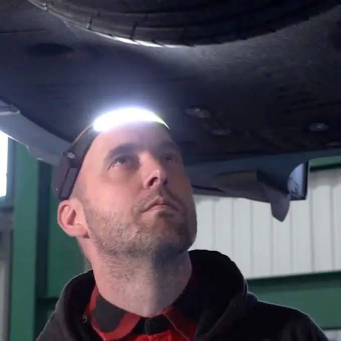 Man looking up at the underside of a vehicle with the wide headlamp beam switched on